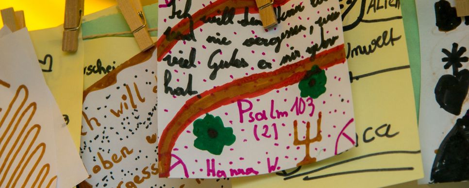 Handgeschriebene und bunt bemalte Zettel hängen an einer Wäscheleine mit Holzklammern.